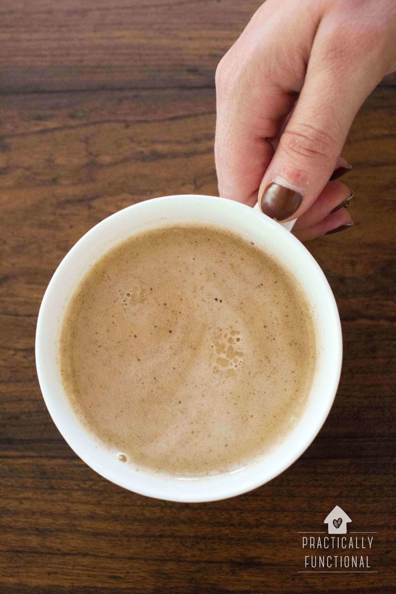homemade butterbeer latte in a white mug held by a woman's hand