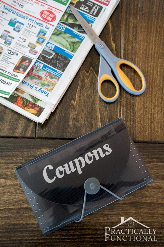 small expandable file folder with the word "coupons" on it on a table with newspaper coupons and scissors