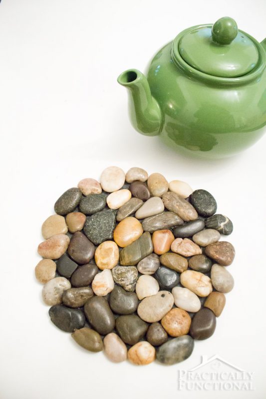 diy river rock trivet and green tea kettle on white background