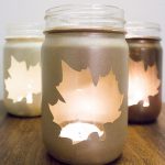 mason jar candle holders spray painted in gold with leaf-shaped unpainted area to see candle through