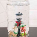 homemade snow globe in a mason jar with reindeer, light post, and presents miniature figurines