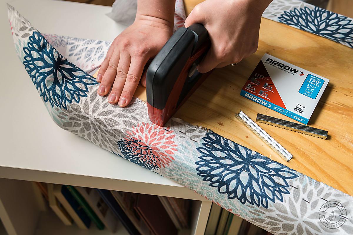 woman stapling upholstery fabric to back of diy bench cushion using arrow t50 red stapler